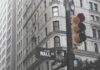 Centralny Rejestr Beneficjentów Rzeczywistych Nowy Jork za dnia, na pierwszym panie sygnalizacja świetlna oraz znak drogowy na skrzyżowaniu ulic Wall Street i Broadway, w tle fragment kamienicy
