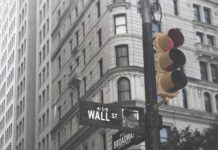 Centralny Rejestr Beneficjentów Rzeczywistych Nowy Jork za dnia, na pierwszym panie sygnalizacja świetlna oraz znak drogowy na skrzyżowaniu ulic Wall Street i Broadway, w tle fragment kamienicy