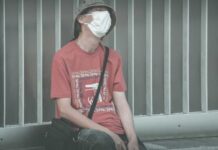 Epidemia COVID-19 a przepisy prawa pracy Zmęczony Człowiek w masce ochronnej siedzi na ławce